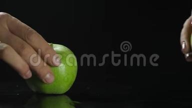 黑<strong>桌子上</strong>的绿苹果水果。 黑色背景。 手<strong>拿起</strong>苹果。 近距离射击